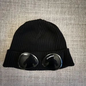 Cp Company mössa - Säljer en äkta cp company mössa. Mössan är i okej skick. Den har några små repor på glaset men de syns knappt. I övrigt är mössan skön och trevlig kan sänka priset vid snabb affär👍🏼 