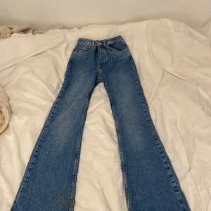 Blå bootcut jeans - Säljer ett par blå bootcut jeans . Klassisk femficksmodell med normal passform och hög midja. Perfekta för dig som gillar en avslappnad och trendig look. De har midjan 24 och längden 30. De är lite slitna längst ner på benen. Är inte helt säker på vart jag köpt de men har för mig att det är från Bikbok