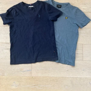 Två t-shirts från Lyle & Scott och U.S. Polo Assn. - Säljer två snygga t-shirts, en blå från Lyle & Scott med gul broderad logga och en mörkblå från U.S. Polo Assn. med broderad logga. Båda har rund hals och korta ärmar. Perfekta för en avslappnad stil.