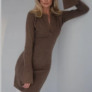 Brun stickad klänning från Adoore - Säljer en brun stickad klänning från Adoore med v-ringning och långa ärmar med utsvängda ärmslut. Klänningen har en mjuk och skön känsla, perfekt för kyligare dagar. Enkel men stilren design som passar till många tillfällen. Använd fåtal gånger .