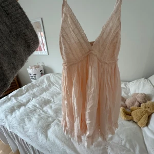 Ljusrosa spetsklänning från urbanoutfitters - Supersöt ljusrosa klänning från urbanoutfitters med broderade spetsdetaljer upptill och v-ringning. Klänningen är ärmlös, har volangkant nertill och är tillverkad i ett lätt, luftigt material. Perfekt för sommarens alla tillfällen!