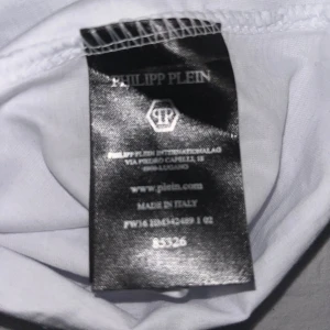 Vit t-shirt med tigerbrodyr från Philipp Plein - Säljer en vit t-shirt från Philipp Plein med en stor, detaljerad tigerbrodyr i svart och guld på bröstet. T-shirten har rund halsringning och korta ärmar. Märkeslogga broderad på axeln. Perfekt för dig som vill sticka ut! Nya modellen av Philip plein!