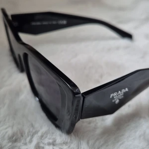 Svarta solglasögon från Prada - Snygga svarta solglasögon från Prada med breda skalmar och rektangulära glas. Klassisk design A kopior!