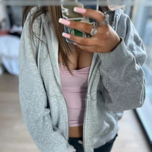 Grå hoodie med dragkedja - Säljer en klassisk grå hoodie med dragkedja och huva. Tröjan har långa ärmar och är i mjukt material, perfekt för en avslappnad stil. Passar till det mesta och är enkel att matcha.