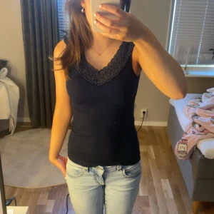 Marinblå ribbad linnetopp med spetskant - Säljer denna marinblåa linnetoppen med v-ringning och dekorativ spetskant längs halsringningen. JÄTTEFIN!!🩷🩷