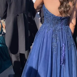 Mörk Blå balklänning  - Hej hej! Tänkte prova att sälja min fina balklänning.  Den är köpt i maj 2024 i Linköping på bröllopshuset. Nypris: 7400kr Klänningen är använd en endaste gång, under balen. Den är i storlek 10 som det står på lappen men eftersom det är som en korsett och man knyter den i ryggen så passar den fler storlekar. Skulle säga att det kan vara storlekarna 36 till 42. För referens: jag är 180 lång, väger 70kg, behövs fler mått är det bara att höra av sig. (Pris kan diskuteras)🩵Skriv för fler frågor/bild