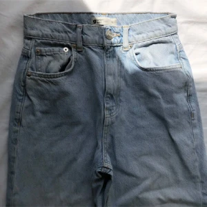 Blå jeans - Blå jeans från Gina tricot med hål i knäna. Innerbenslängd ca 76cm. Midjemått 64cm.  Ankelmått ca 36cm. Vikt ca 585g.