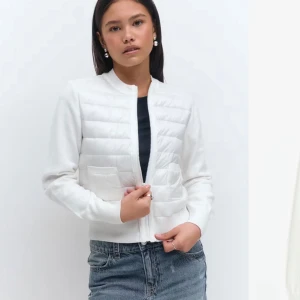 Vit quiltad cardigan jacka med dragkedja - Skit Snygg vit cardigan jacka med quiltade partier framtill och två fickor.Liknar den från moncler. Jackan har dragkedja och långa ärmar. Perfekt för lager-på-lager och enkel att matcha till olika outfits. Helt ny och oanvänd (Storlek 170 passar mig som är 161 och bär xs/s. )