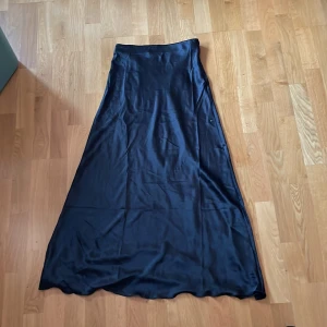 Svart långkjol i satin från Lager 157 - Säljer en svart långkjol i glansigt satinmaterial från Lager 157 i storlek S. Kjolen har en elegant, lätt utställd passform och är perfekt för dig som gillar stilrena plagg med lyxig känsla. Kjolen är använder 1 gång och är i ny skick. Skriv om ni vill ha mer information och om ni har frågor💕