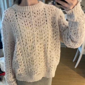 Beige stickad tröja från Vero Moda - Säljer en superfin beige stickad tröja från Vero Moda med ett snyggt hålmönster. Tröjan har lång ärm, rund halsringning och är riktigt mjuk och mysig. Perfekt att styla med jeans eller kjol för en chill look.