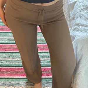 Lounge pants - Säljer ett par beiga byxor med med raka, lätt utsvängda ben. Byxorna har resår och dragsko i midjan för extra komfort. Perfekta för varmare dagar och har en avslappnad stil.