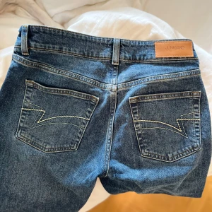 Blå jeans från Junkyard - Säljer ett par klassiska blå jeans från Junkyard med låg midja. Jeansen har snygga bakfickor med vit söm. Säljer då de är lite för stora för mig i midjan. Använda runt 4 gånger!