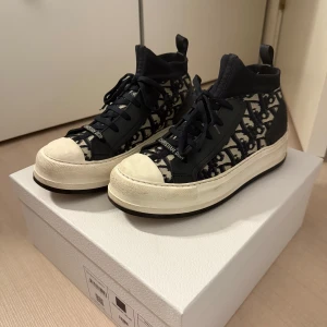 Christian Dior sneakers - Snygga sneakers från Christian Dior med mörkblå och vita monogramdetaljer. Det är den högre modellen, sparsamt använda men såklart några små skavanker som jag tror går bort med lite tvätt. Köpta på NK Göteborg i butiken collage, nypris 12.450 kr. Kvitto samt box finns! Pris kan diskuteras!