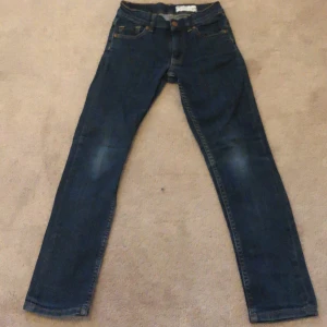 Mörkblå jeansbyxor från Polarn O. Pyret - Snygga mörkblå jeansbyxor från Polarn O. Pyret med klassisk femficksdesign och raka ben. Byxorna har orangea sömmar och en svart läderpatch bak i midjan. Perfekta för en avslappnad och stilren look. Priset går att diskutera och är inte hugget i sten . 👍