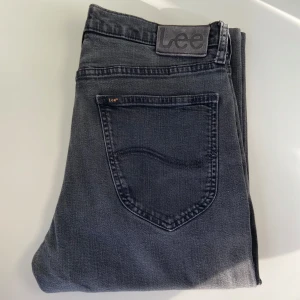Lee Jeans - Klassiska svarta jeans från Lee i modellen med rak passform. Tidlös design som passar till allt – både till vardags och lite mer uppklätt. Mjukt och slitstarkt denim med lätt stretch som gör dem bekväma att bära hela dagen.  Storlek: W34&L32  Färg: Svart Skick: Mycket fint skick – inga fläckar, hål eller synligt slitage Passform: Rak/regular fit