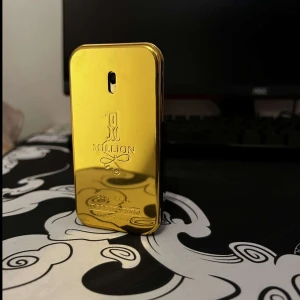 1 Million Eau de Toilette herrparfym - Säljer en ikonisk herrparfym från Paco Rabanne, 1 Million. Flaskan är guldig och formad som en guldtacka med präglad logotyp och text. Doften är känd för sin fräscha, kryddiga och maskulina karaktär.