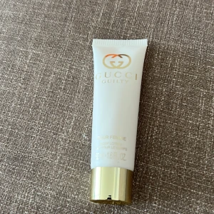 Gucci Guilty Pour Femme Body Lotion - Gucci Guilty Pour Femme body lotion i en vit tub med gulddetaljer och skruvlock. Tuben rymmer 50 ml och har en elegant design med Gucci-loggan i guld på framsidan. Perfekt för att komplettera din doftgarderob.