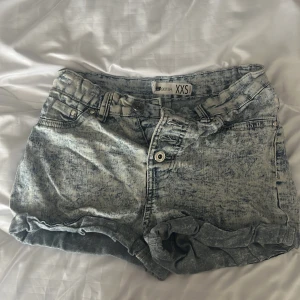 Acid wash jeansshorts från FB Sister - Snygga acid wash jeansshorts från FB Sister i storlek XXS. De har klassisk femficksdesign, knapp- och dragkedjestängning samt uppvikta benslut. Perfekta för en cool och avslappnad stil. 🙌