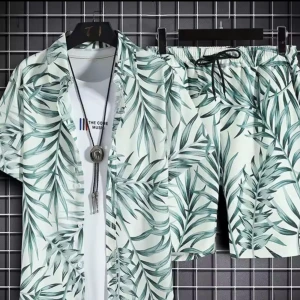 Grön- och vitmönstrad skjorta och shorts med palmblad - Kortärmad skjorta med grönt palmbladsmönster på vit botten. Skjortan har klassisk krage och knappar framtill, perfekt för varma dagar. Matchande shorts ingår.