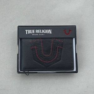 Svart plånbok från True Religion - Snygg svart plånbok från True Religion med ikonisk röd söm och logga på framsidan. Kommer i en snygg ask.