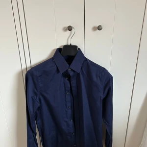 Gant skjorta - Säljer en klassisk mörkblå skjorta från GANT i storlek S. Skjortan har lång ärm, knappar framtill och en stilren design som passar till många tillfällen. Perfekt för dig som gillar en tidlös och enkel look.