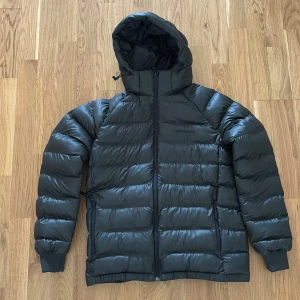 Mörkgrön dunjacka från Peak Performance - Säljer en mörkgrön dunjacka från Peak Performance med huva och dragkedja. Perfekt till höst/vinter. Jackan är använd endast en gång så den är som ny!