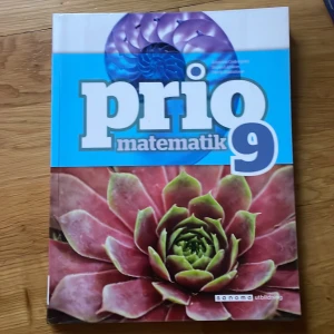 Prio Matematik 9 - Säljer läroboken Prio Matematik 9 från Sanoma Utbildning. Omslaget har en blå och vit design med stora bokstäver samt bilder på en lila snäcka och en grön-röd växt. Perfekt för dig som pluggar matte i nian.