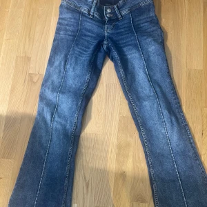 Blå bootcut jeans med låg midja - Säljer ett par blå bootcut jeans med låg midja och dubbla knappar framtill. På bilderna syns inte att de är jättelågmidjade och på bild 3-4 är i bilder från webben och ett i provrummet (där är det mörkare) köptes för 500kr och säljer då dessa fina jeans inte kommer till användning längre. Om bättre bilder behövs så är det bara att skriva! Byxornas nedre del är lite trampade (se bild 5)❤️