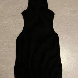 Svart ribbad ärmlös polotopp från H&M - Säljer en svart ribbad polotopp från H&M. Toppen är ärmlös och har en tight passform med hög krage. Använd ca 2-3 gånger. Perfekt att styla med jeans eller kjol för en trendig look. Kan gå ner i pris vid snabb affär!💕