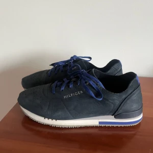 Mörkblå sneakers från Tommy Hilfiger - Snygga mörkblå sneakers från Tommy Hilfiger med vita och blå detaljer på sulan. Perfekta för en stilren look!😊