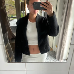 Svart  jacka med dragkedja - Säljer en svart croppad jacka med dragkedja framtill. Jackan har lång ärm och en enkel, stilren design. Passformen är normal och materialet känns mjukt och lite tjockare, perfekt för kyligare dagar.