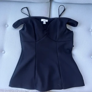 Svart topp - Säljer en svart figurnära topp från hm med smala axelband. Toppen har en elegant och enkel design som passar perfekt till många olika outfits. Endast använd en gång💕