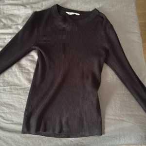 Svart ribbad långärmad tröja från C - Säljer en svart ribbad långärmad tröja från C i storlek XS. Tröjan har en rund halsringning och är figurnära i modellen. Perfekt basplagg till garderoben och enkel att matcha med olika outfits. Helt oanvänd.