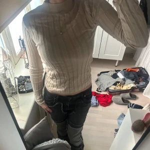 Beige ribbad långärmad tröja - Säljer en beige ribbad långärmad tröja med rund halsringning. Tröjan har en tight passform och är perfekt för lager-på-lager. Enkel och stilren design som passar till mycket.