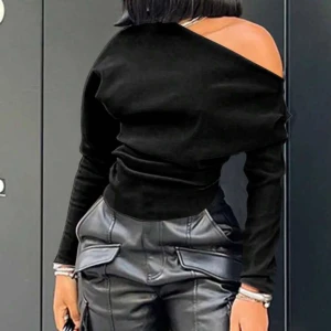 Svart oneshoulder topp - Snygg svart långärmad topp med oneshoulder-design. Toppen har en asymmetrisk halsringning som visar ena axeln och är tillverkad i ett mjukt, stretchigt material. Perfekt för dig som vill ha en stilren och trendig look.