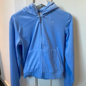 Blå velour hoodie från Juicy Couture - Säljer en ljusblå hoodie i mjuk velour från Juicy Couture. Helt oanvänd, är i storlek 14/15 år är som en xxs/xs!