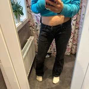 Low waisted jeans  - Snygga svarta jeans från Foranna med bootcut ben och klassisk femficksdesign. Jeansen har coola bakfickor med unik form och detaljerade sömmar. Tillverkade i slitstarkt jeanstyg med metallknappar och bälteshällor. Perfekta för en stilren och avslappnad look. 