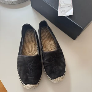 Svarta espadrilles från Saint Laurent - Svarta espdrilles i mocka från Saint Laurent i storlek 37. I fint skick och har mer att ge! Köpta på ABCD som tidigare låg intill Stureplan. Box såväl som kvitto följer med vid köp. 