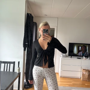 Svart omlottkofta med knyt - Svart långärmad omlottkofta med djup v-ringning och knyt framtill. Använd endast en gång