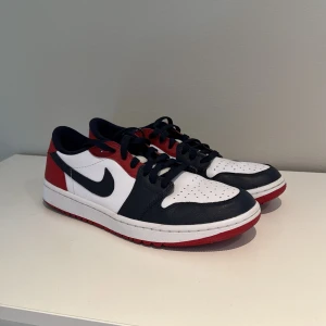 Nike Air Jordan 1 Low Golf röd/blå/vit - !!jag har använt dom 2 gånger!! 1200-: ny pris!! Öppen för prisförslag!!Nike Air Jordan 1 Low Golf i en clean färgkombo av vitt, marinblått och rött. Klassisk siluett med perforerad tå, snörning och ikoniska Air Jordan-detaljer på hälen. Ovandel i skinn och syntet, perfekt för dig som vill sticka ut på golfbanan.