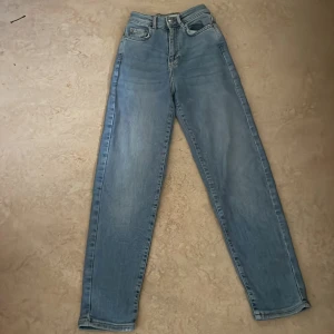 Ljusblå high waist jeans från Gina Tricot - Säljer ett par ljusblå high waist jeans från Gina Tricot, modell Perfect Jeans. Klassisk femficksdesign, raka ben och dragkedja i gylfen. Jeansen är i mjuk bomullsdenim och har en snygg, enkel look som passar till allt.