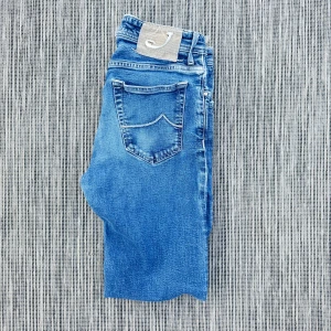 Jacob Cohen  - Snygga blå jeans med klassisk femficksdesign och ljus tvätt. Jeansen har en bakficka med dekorativ söm och en beige patch med broderad J på linningen. Perfekta för en avslappnad och trendig look.!AI BESKRVINING! Om ni vill ha fler bilder eller om ni har andra funderingar och frågor skriv.
