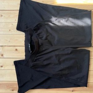 Svarta ribbade byxor XS från LGL - Svarta ribbade byxor från LGL i storlek XS. Byxorna har en elastisk midja och är tillverkade i ett mjukt, stretchigt material. De har raka ben och en enkel, clean look som passar till många olika stilar.