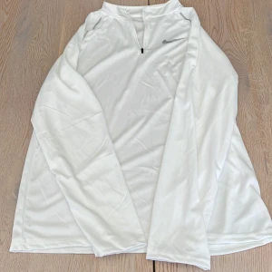 Vit långärmad Nike half zip-tröja - Vit långärmad tröja från Nike med halv zip som passar perfekt för träning eller chill. Enkel och clean design med relaxed fit.