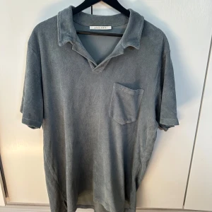 Grå frotté pikétröja A Day's March - Säljer en grå pikétröja från A Day's March i mjuk frotté. Tröjan har klassisk krage, korta ärmar och en bröstficka. 