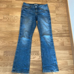 Blå bootcut jeans från Gina Tricot - Näst intill helt nya, köptes i slutet av maj.jeans från Gina Tricot i bootcut-modell. Jeansen har låg midja, coola slitningar och knappar på baksidan 