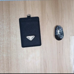 Svart  plånbok i skinn - Minimalistisk svart plånbok  i exklusivt skinn med ikonisk metallogo framtill. Perfekt för kort och småsaker, stilren och smidig att ha med sig överallt.