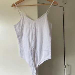 Vit linnetopp med smala band - Enkel och stilren vit linnetopp med smala axelband och v-ringning. Perfekt att matcha med jeans eller kjol för en clean look.