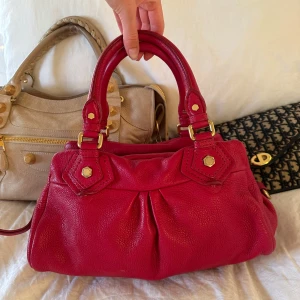 Röd Q Classic Baby Groove väska! - Köp helst via min vinted 🤍Snyggaste röda handväskan i äkta läder från Marc by Marc Jacobs. Den ikoniska modellen Q Classic Baby Groove! En populär och eftertraktad vintagemodell med gulddetaljer och dubbla handtag. Väskan är i fint skick men emblemet saknas. Fint lyster i lädret och en otrolig röd statement färg. Några små märken på lädret vid handtagen som syns på bilderna men helhetsintrycket är mycket välbevarat 🤍 Mått: 34x18x12 cm (undersida) Kan hämtas hemma hos mig i Nacka eller skickas 🤍