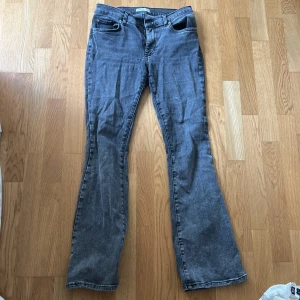 Grå bootcut jeans med slitningar - Grå jeans med bootcut passform och klassisk femficksdesign. Jeansen har en snygg, lite tvättad look och är tillverkade i denim. Dock har jeansen hål längst upp mellan benen pga slitning. Men det syns inte när man går